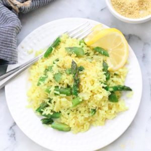 overhead photo of single serving of lemon rice on a white plate with lemon slice garnish