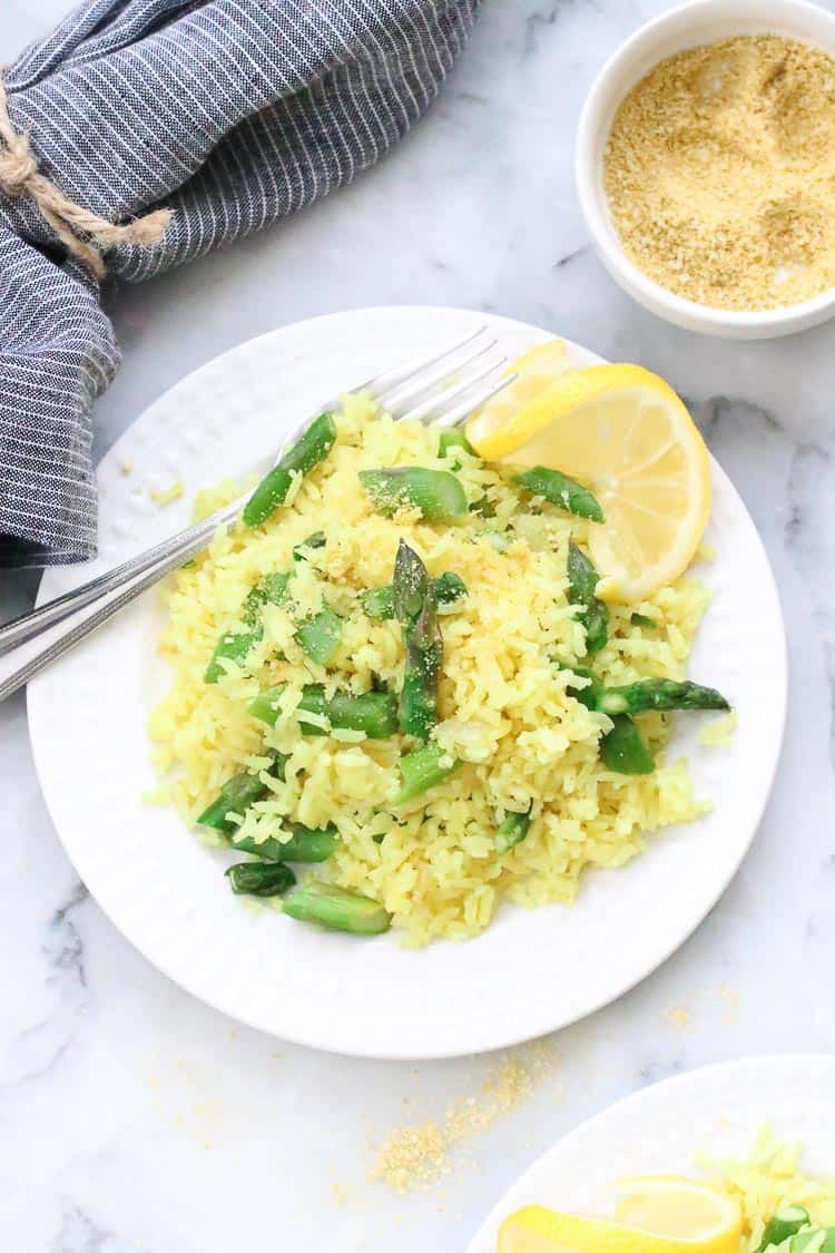 overhead photo of lemon rice with chopped asparagus on white plate with fork 