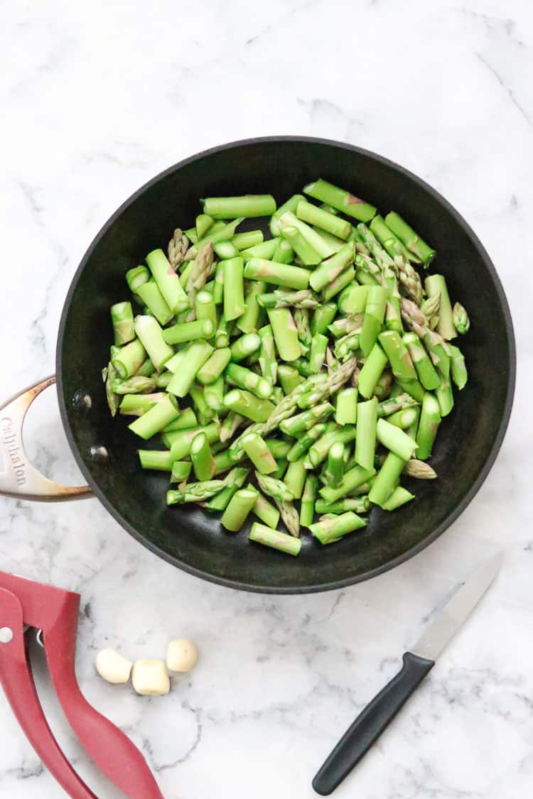 overhead shot of one inch pieces of asparagus in skillet for lemon rice topping