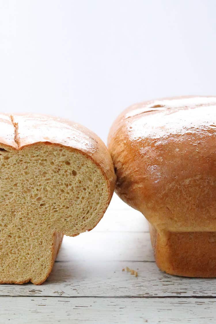 side shot of one sliced and one whole loaf of whole wheat bread side by side