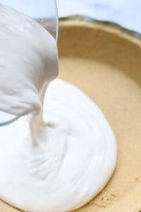 pouring dairy-free cheesecake mixture into a pie crust