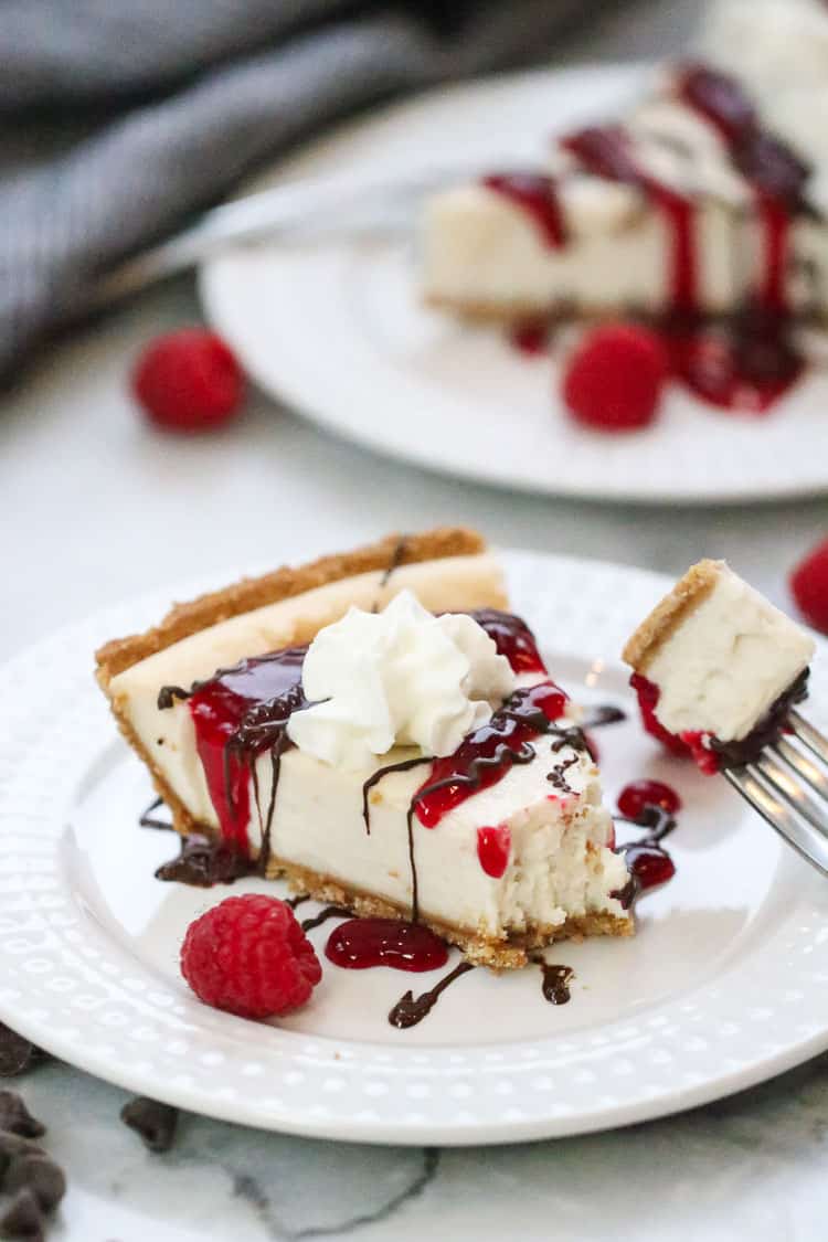 vegan cheesecake sliced on a plate with a spot of whip cream and drizzle of chocolate