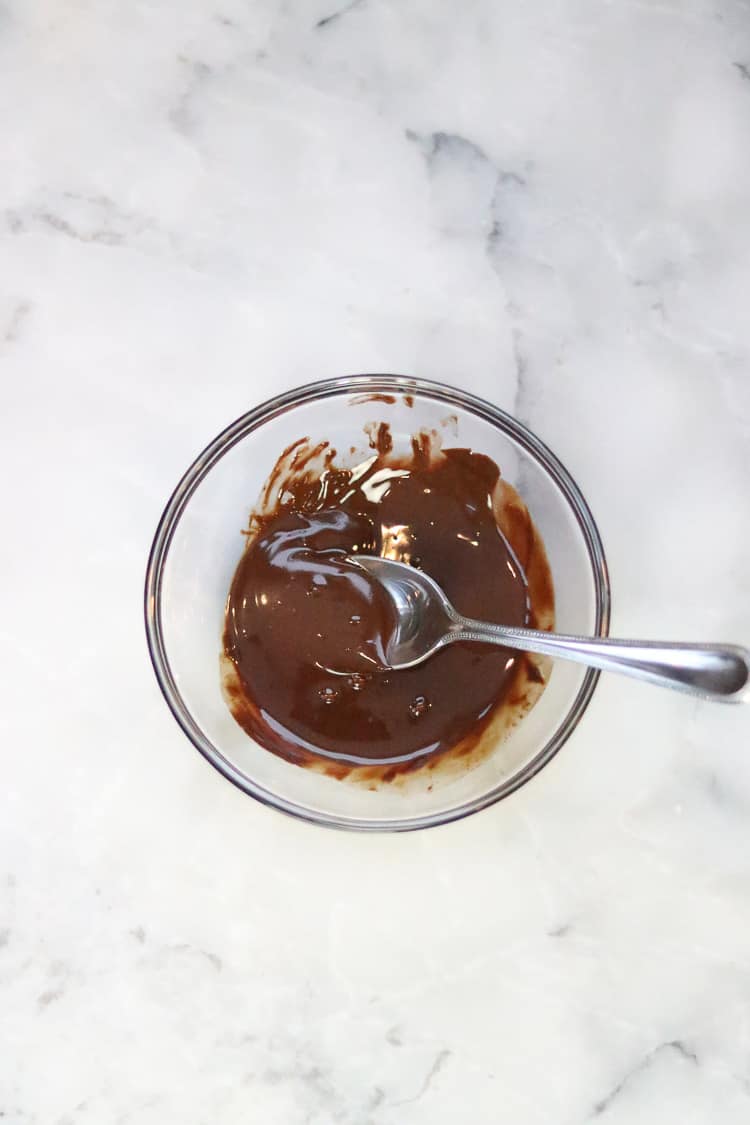 melted chocolate in a clear bowl with a silver spoon