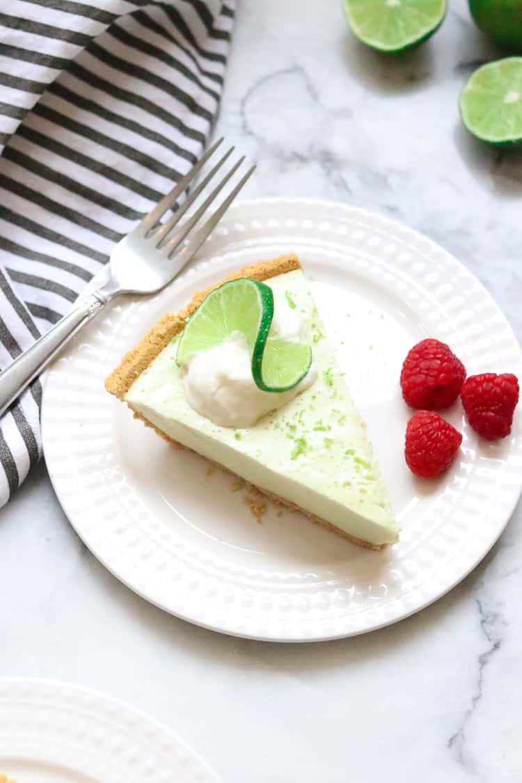 overhead shot of vegan key lime pie slice on white plate with striped napkin beside