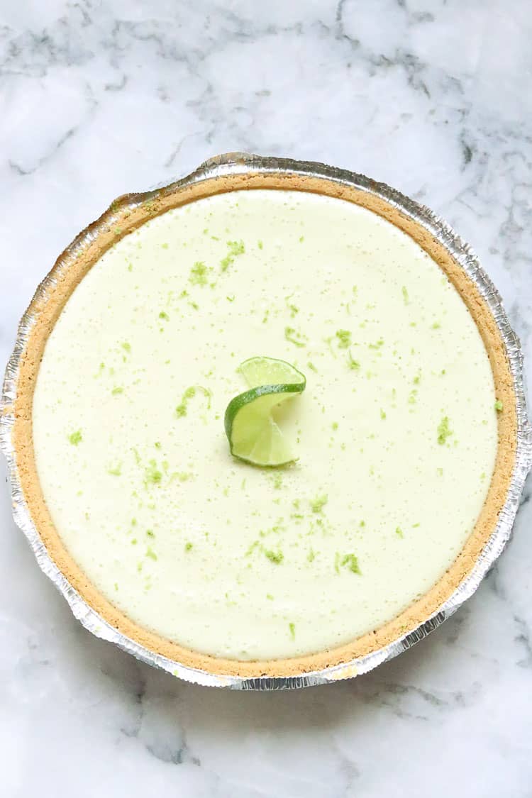 overhead shot of vegan key lime pie with fresh lime slice and grated lime zest as garnish