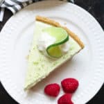 overhead shot of vegan key lime pie on a white plate and a black background