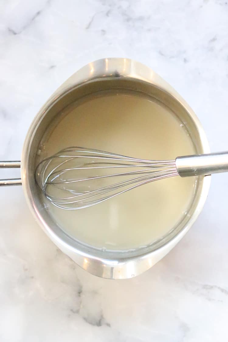overhead shot of water and agar in small silver sauce pan with whisk