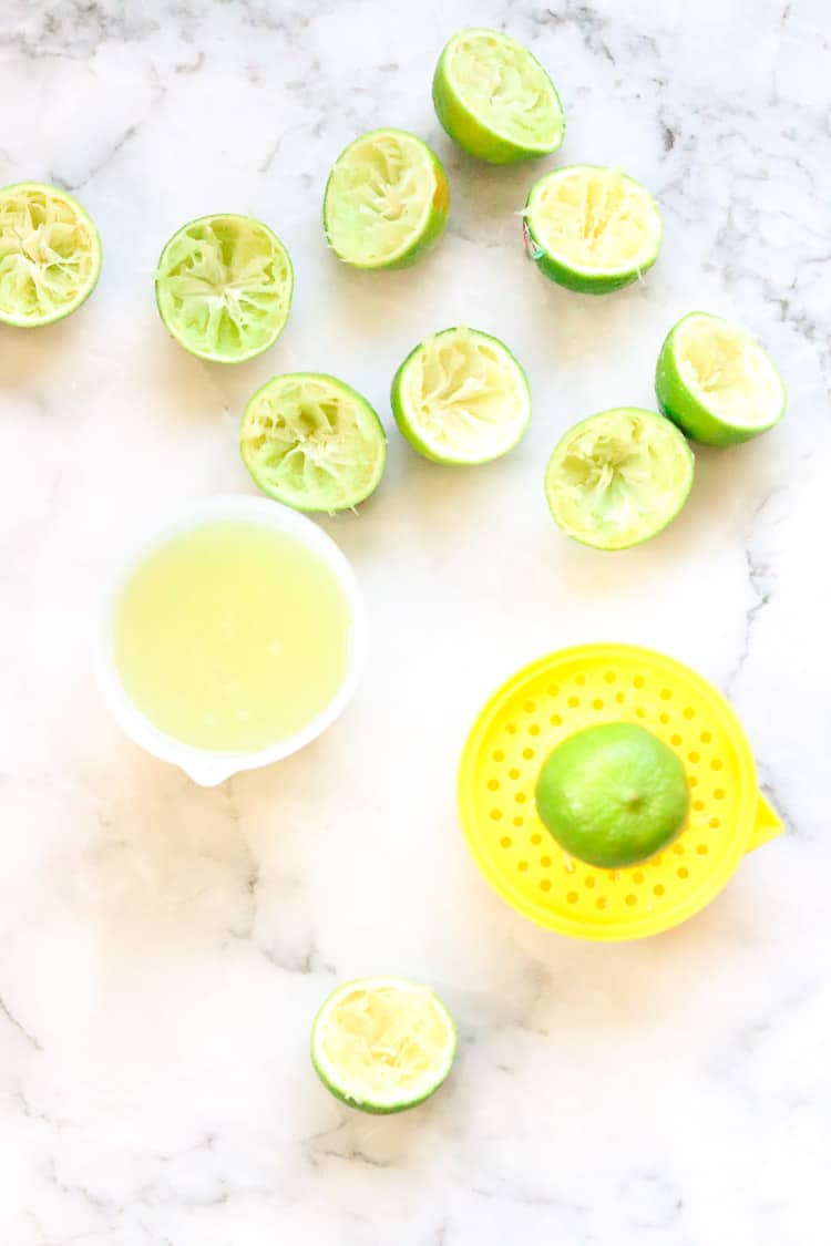 wide overhead shot of sliced and squeezed limes and lime juice for vegan key lime pie