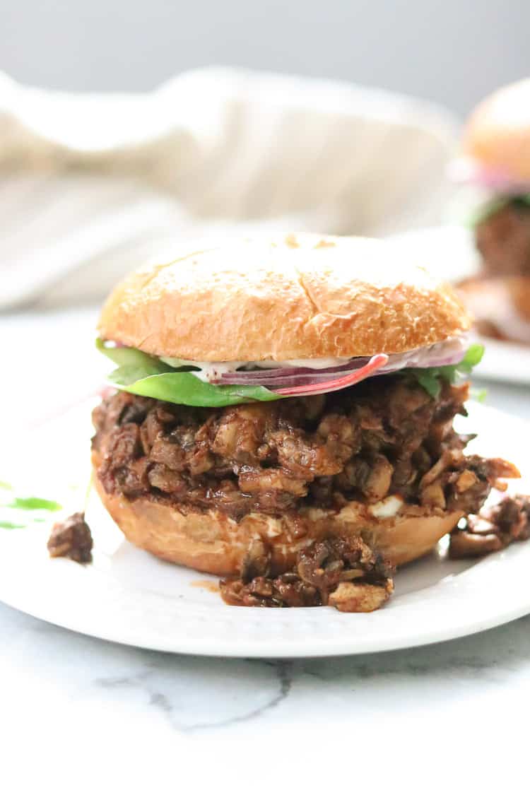 side shot of mushroom sandwich with spinach and red onion on a round bun