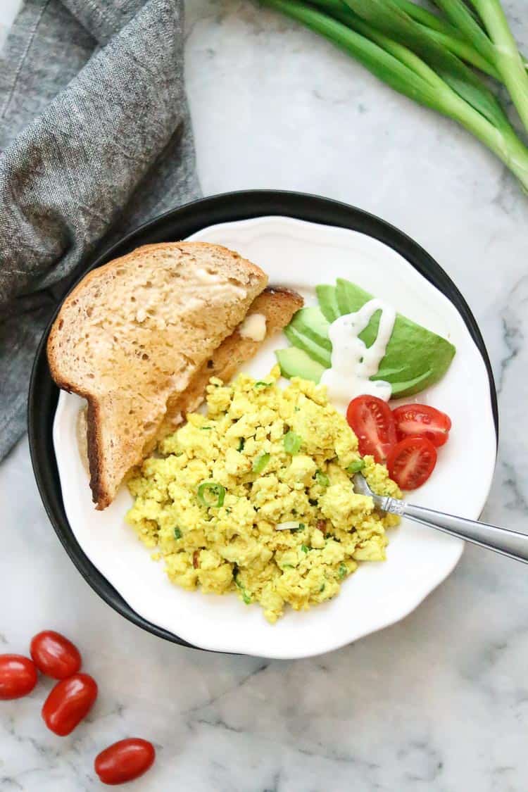 overhead shot of tofu scramble served up on a white plate with a gray napkin beside