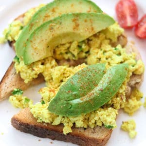 overhead shot of tofu scramble on toast topped with slices of avocado