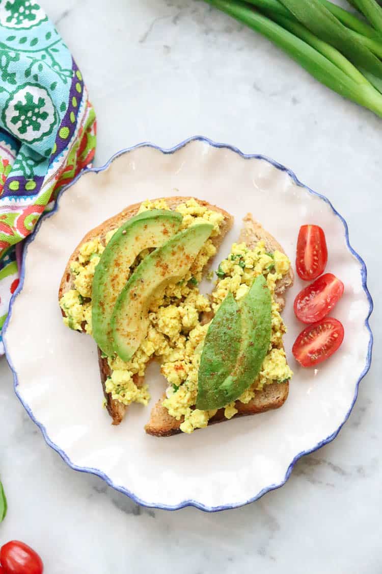 overhead shot of scrambled tofu and avocado on toast on a blue rimmed plate