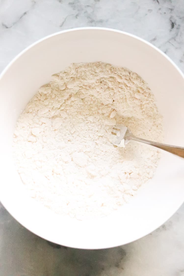 overhead shot of flour mixture for vegan scones in a white bowl with fork