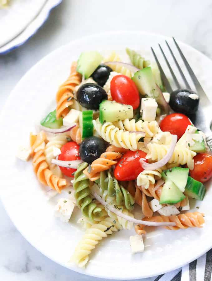 overhead closeup shot of vegan pasta salad on a white plate with a fork