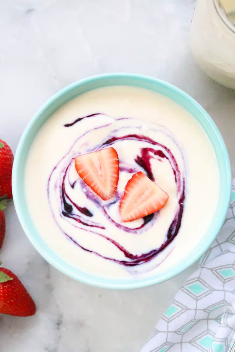 overhead shot of vegan yogurt in bowl with sliced strawberries and berry fruit swirl