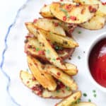 closeup overhead shot vegan baked potato wedges on a white plate with a blue edge