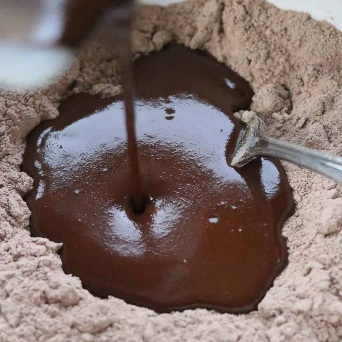 Adding melted chocolate to brownie batter.
