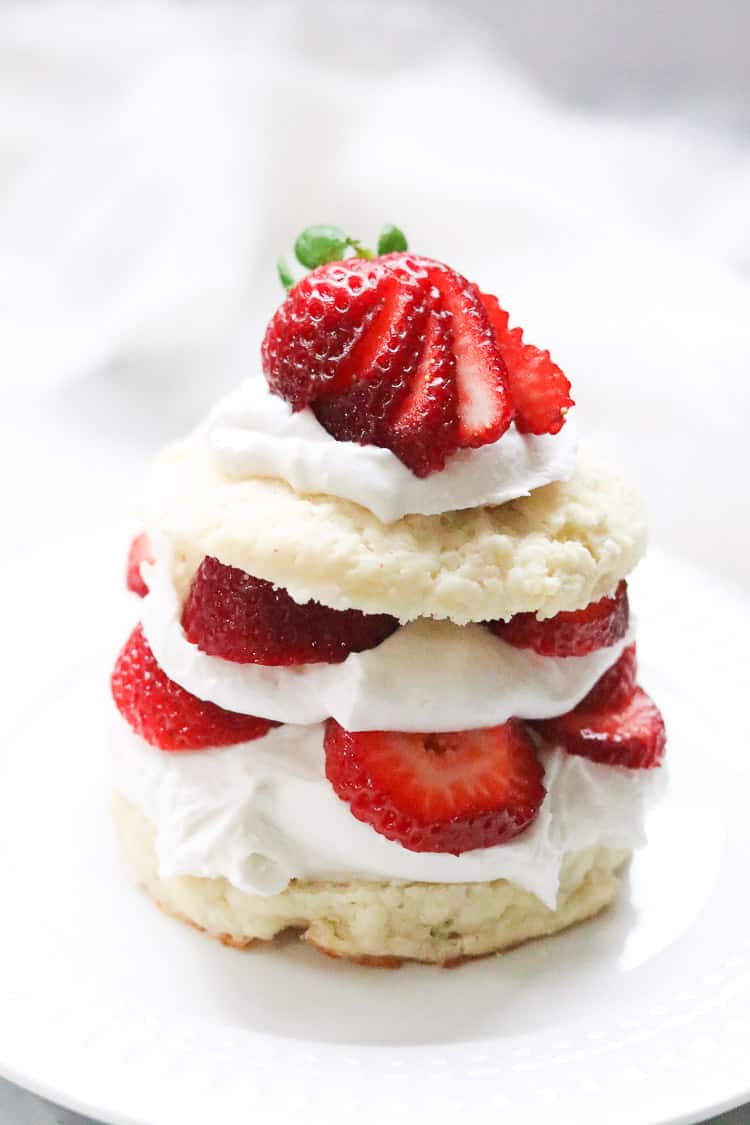 Stack of vegan strawberry shortcake biscuits with coconut whipped cream. 