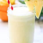 side shot of virgin pina colada with coconut milk in a mason jar with striped straw and pineapple slice