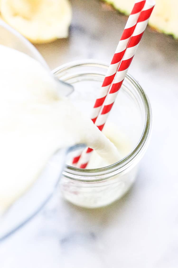 overhead shot of virgin pina colada with coconut milk being poured into pint jar