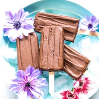 overhead shot of several fudgesicles on a bed of ice surrounded by flowers