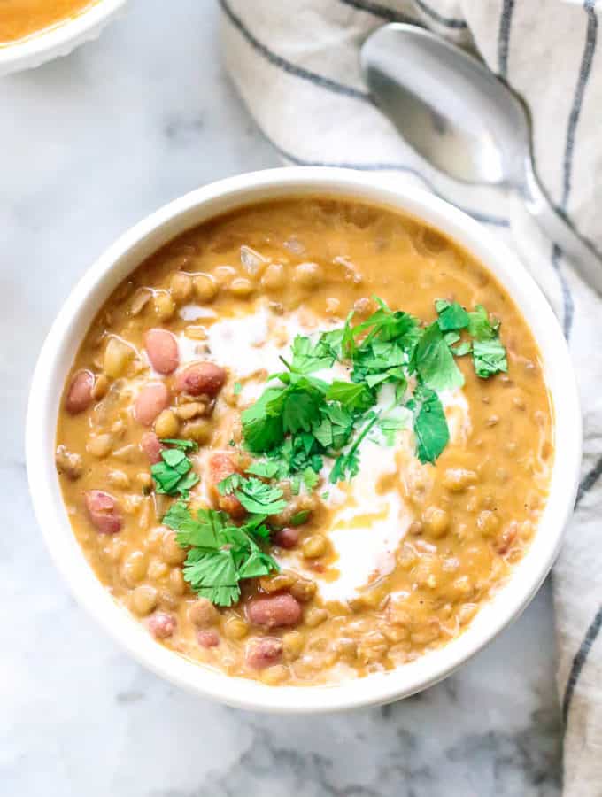 overhead photo of madras lentils in a white bowl with garnish of cilantro and cilantro