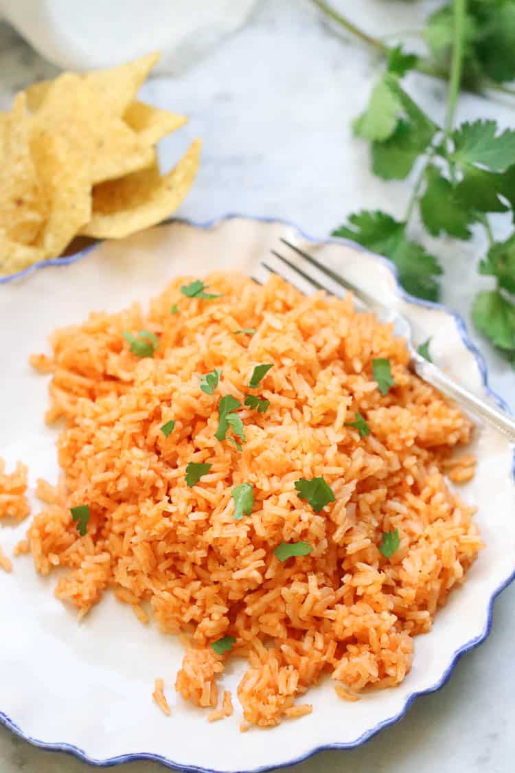 overhead shot of vegan Mexican rice with parsley pieces on a white plate with a blue edge