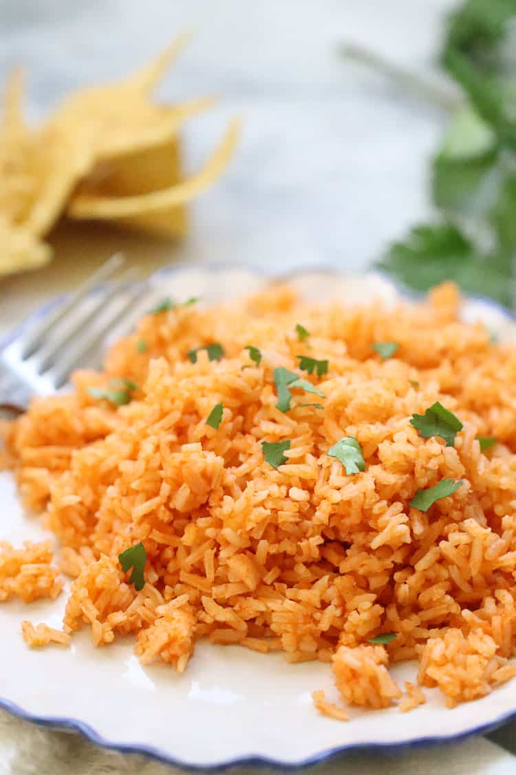 side closeup shot of vegan Mexican rice on a blue rimmed plate with fresh parsley pieces sprinkled over rice