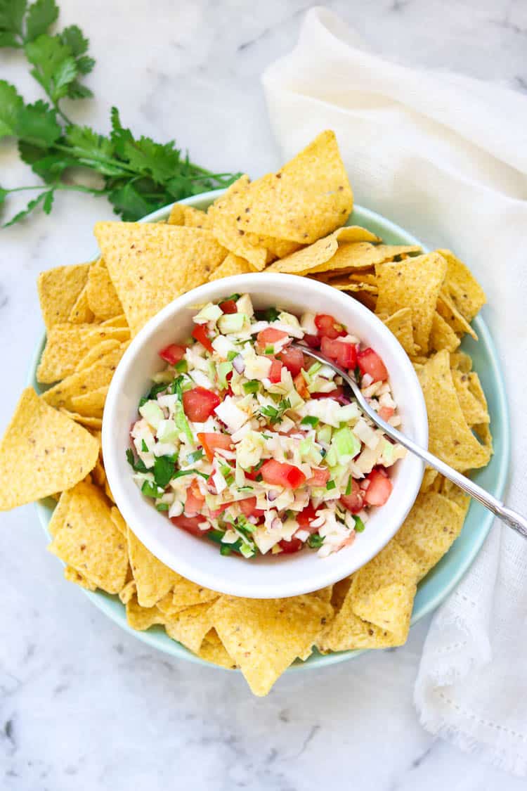 wide overhead shot of cabbage salsa in a white bowl with cilantro and a white napkin nearby