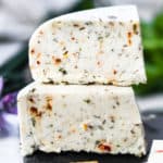 closeup side view of two blocks of vegan herbed cheese stacked with crackers in front