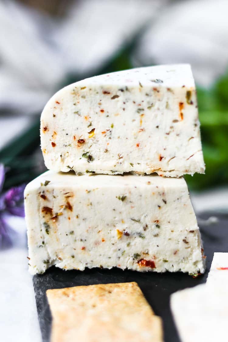 side closeup of chunks of vegan cheese with herbs showing detail and texture of cheese