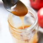 side overhead shot of vegan caramel sauce being drizzled off of silver spoon into jar