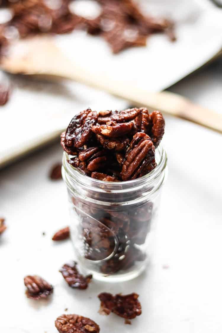 side shot of candied pecans stacked high in a half-pint sized canning jar