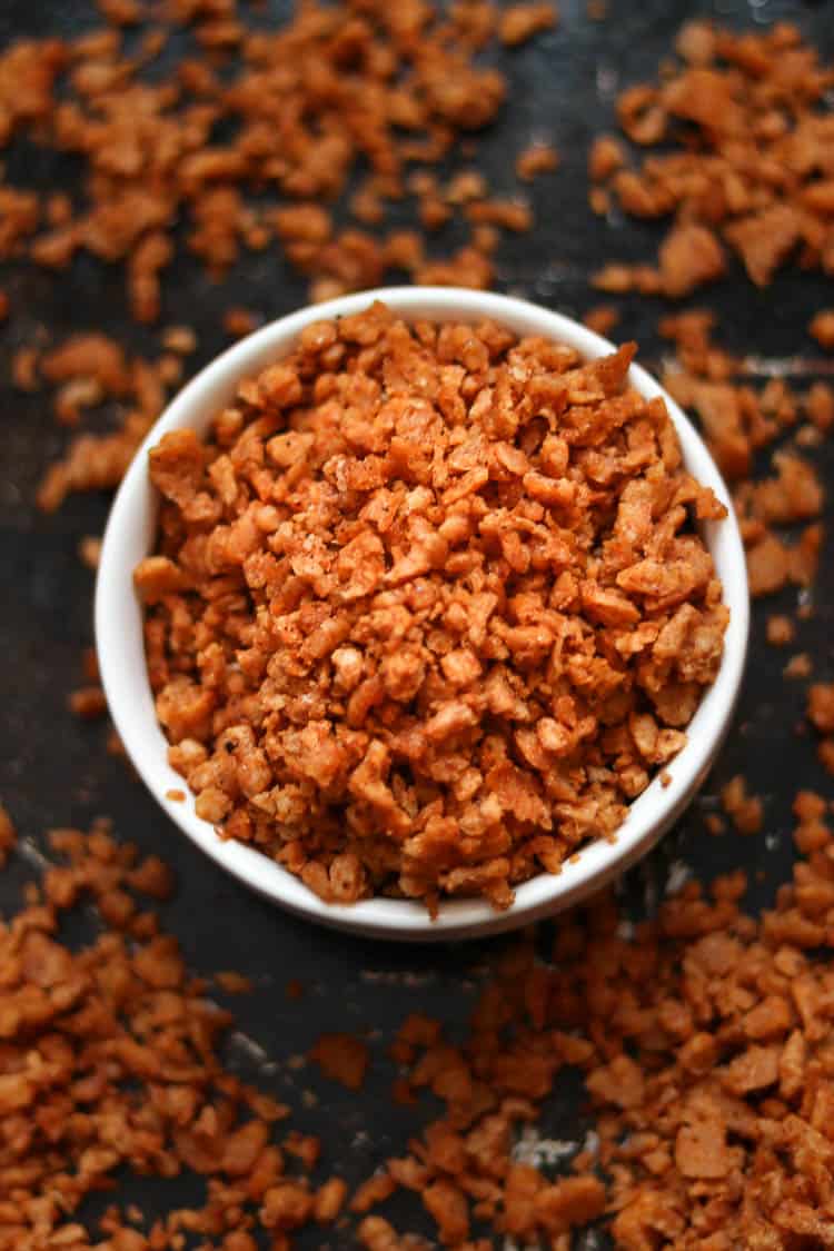 overhead shot of vegan bacon bits in a white bowl setting on a black backing tray