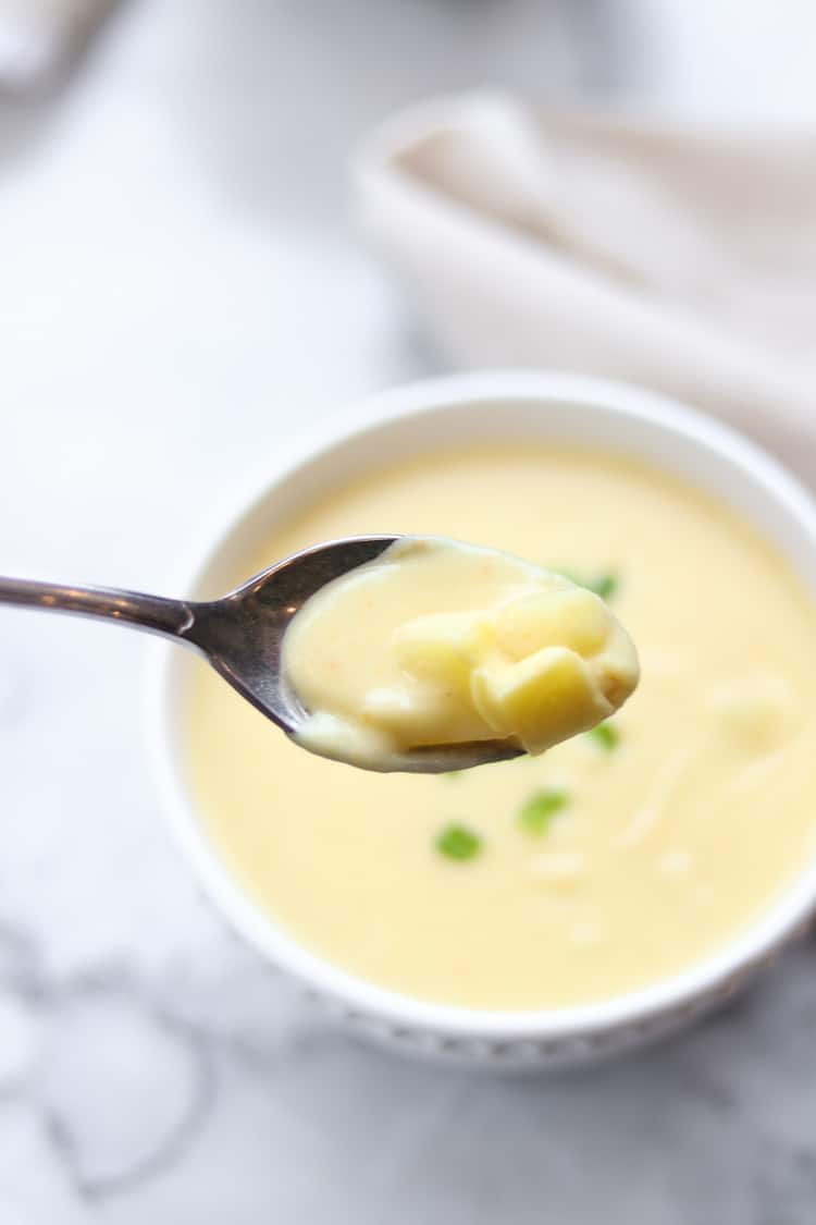 closeup shot of spoonful of potato soup showing texture of potato chunks in creamy soup base