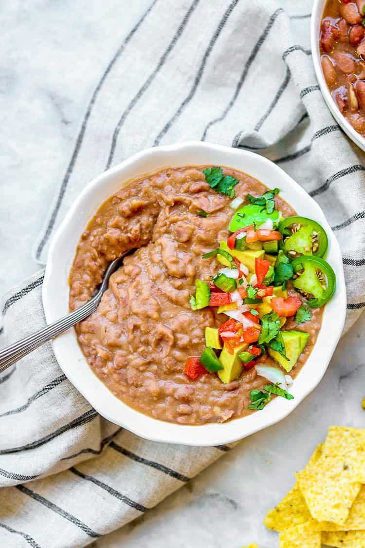 bowl of vegetarian pinto beans topped with salsa and jalapenos