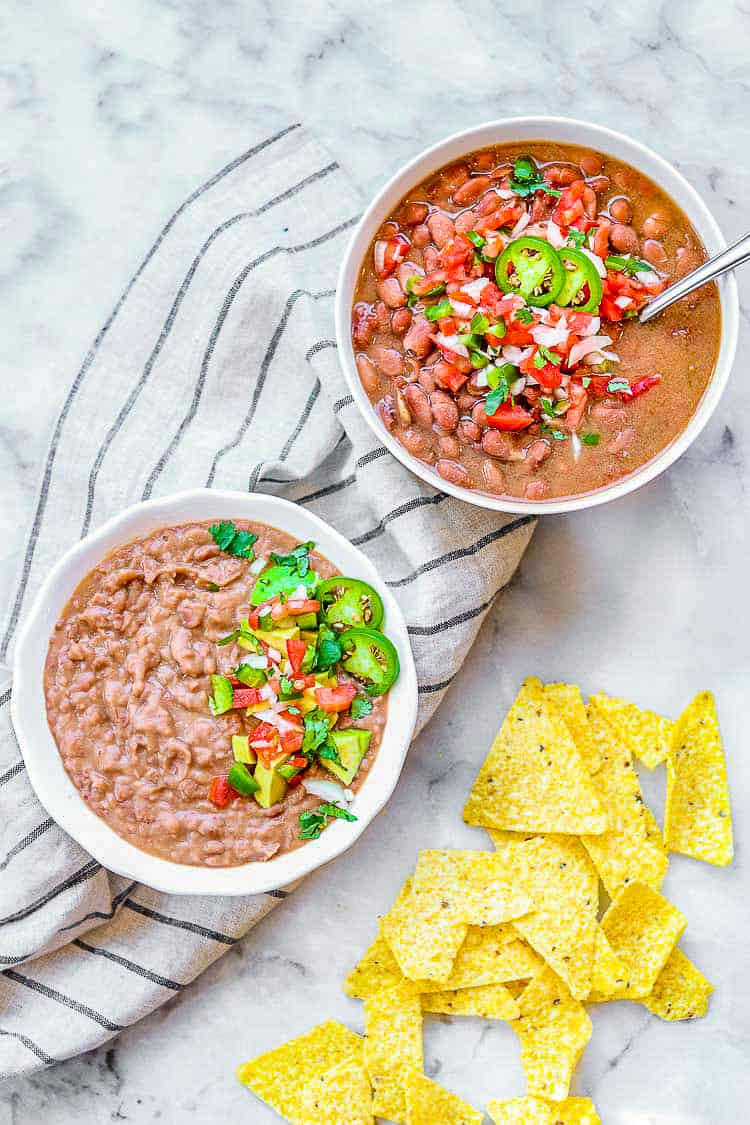 2 bowls of pinto beans, each topped with salsa and sliced jalapenos