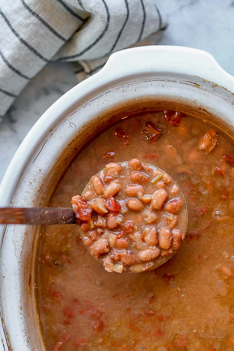 ladle of healthy pinto beans over a crock pot of pinto beans