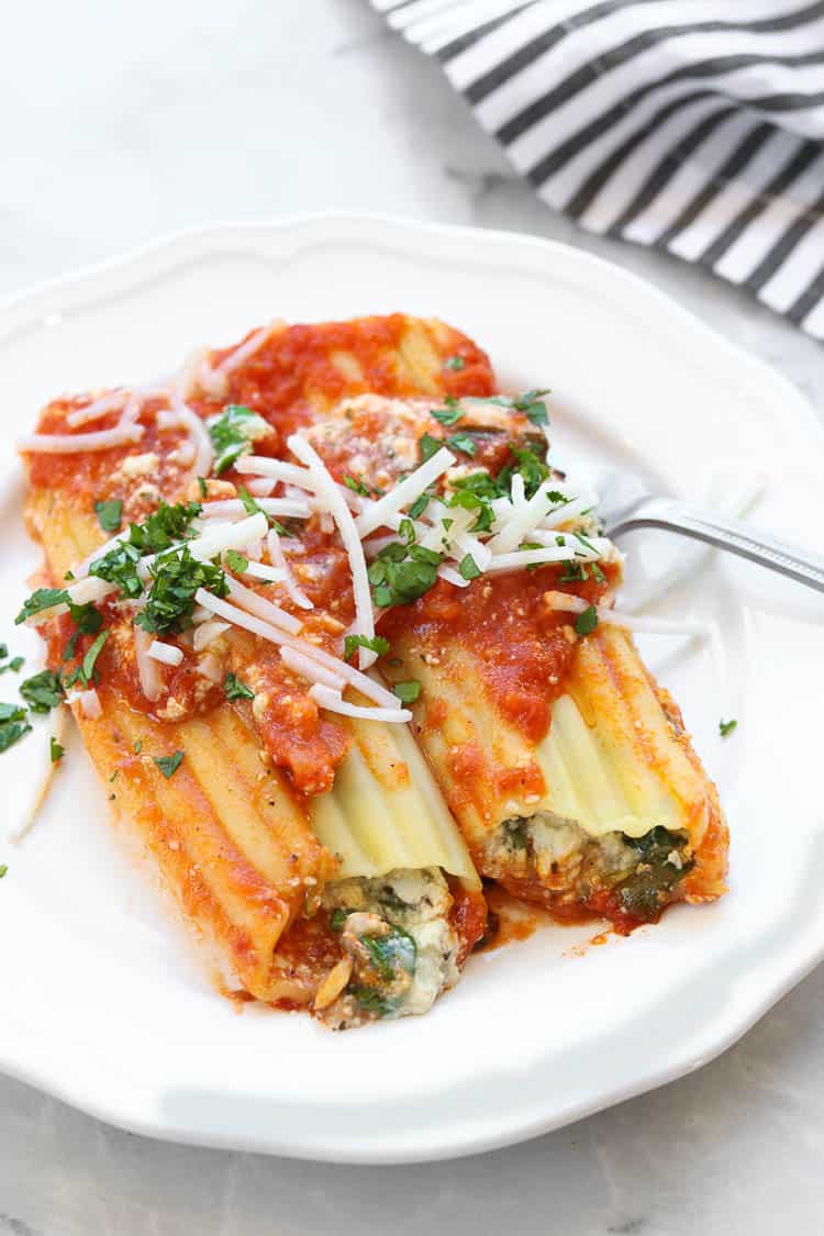 Two vegan manicotti shells on a white plate.