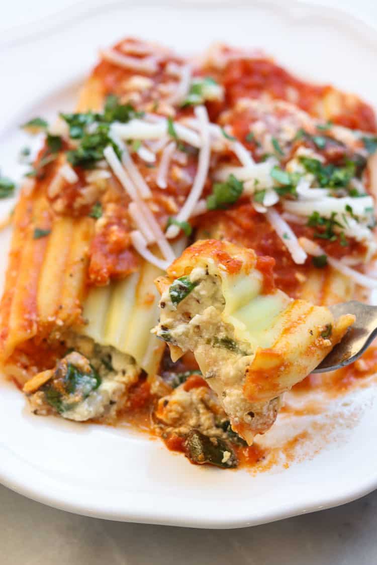 Vegan manicotti showing a bite held up on a fork.