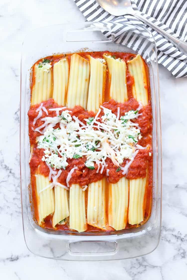 Vegan manicotti in a baking dish on a marble background.