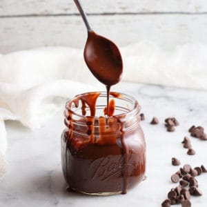 side overhead photo showing chocolate sauce dripping from silver spoon into pint jar