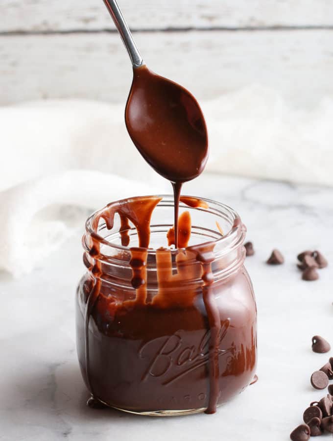 side overhead photo showing chocolate sauce dripping from silver spoon into pint jar