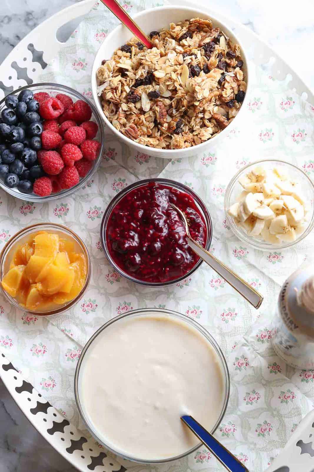 wide overhead photo of fruit, granola, and whipped cream on a tray