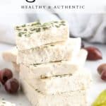 side closeup shot of vegan feta blocks stacked with greek olives and peppers beside with text overlay for pinterest