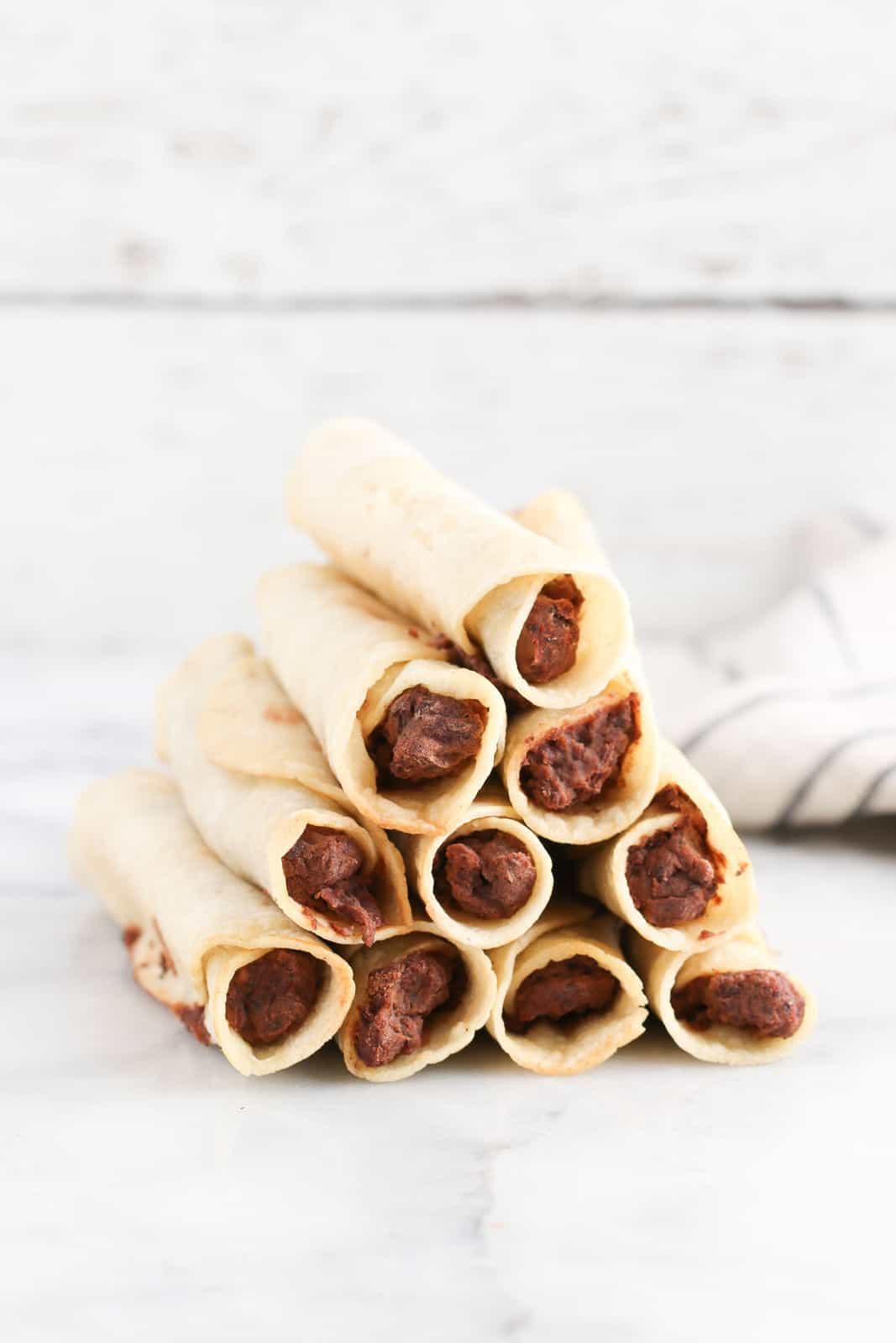 Stack of black bean taquitos with corn tortillas