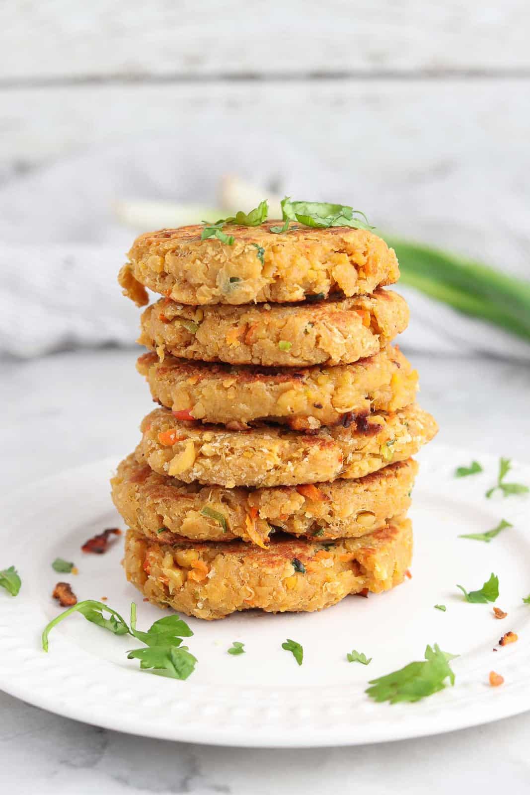 stack of vegan chickpea patties on a plate with herbs