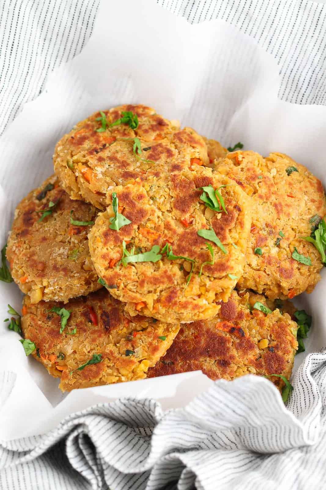 A bunch of chickpea burger patties piled onto parchment paper