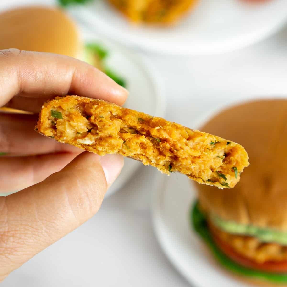 hand holding vegan lentil patty cut in half to show inside texture