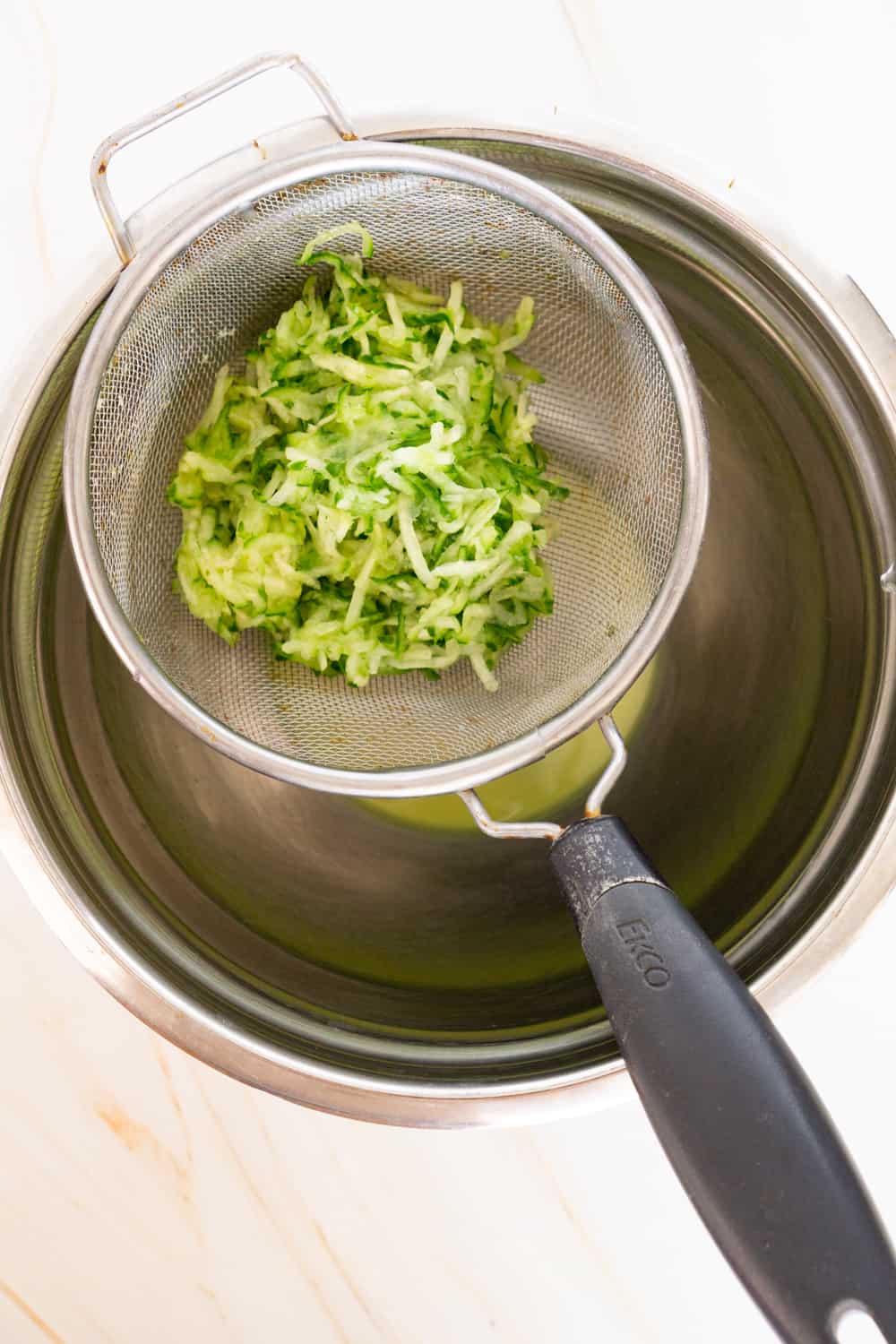 grated cucumber in a colander over a bowl